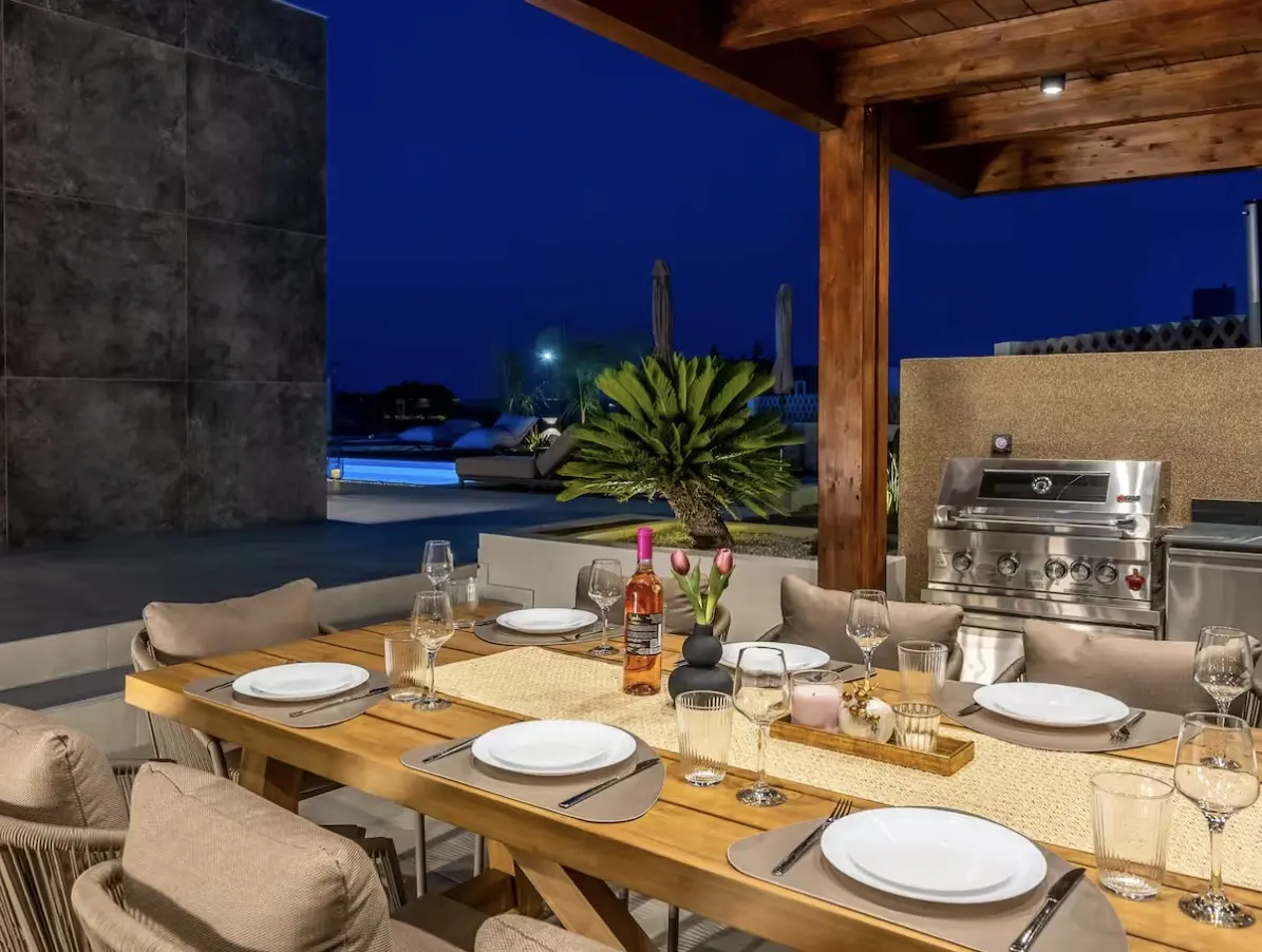 Outdoor dining table laid for dinner beside the villa pool